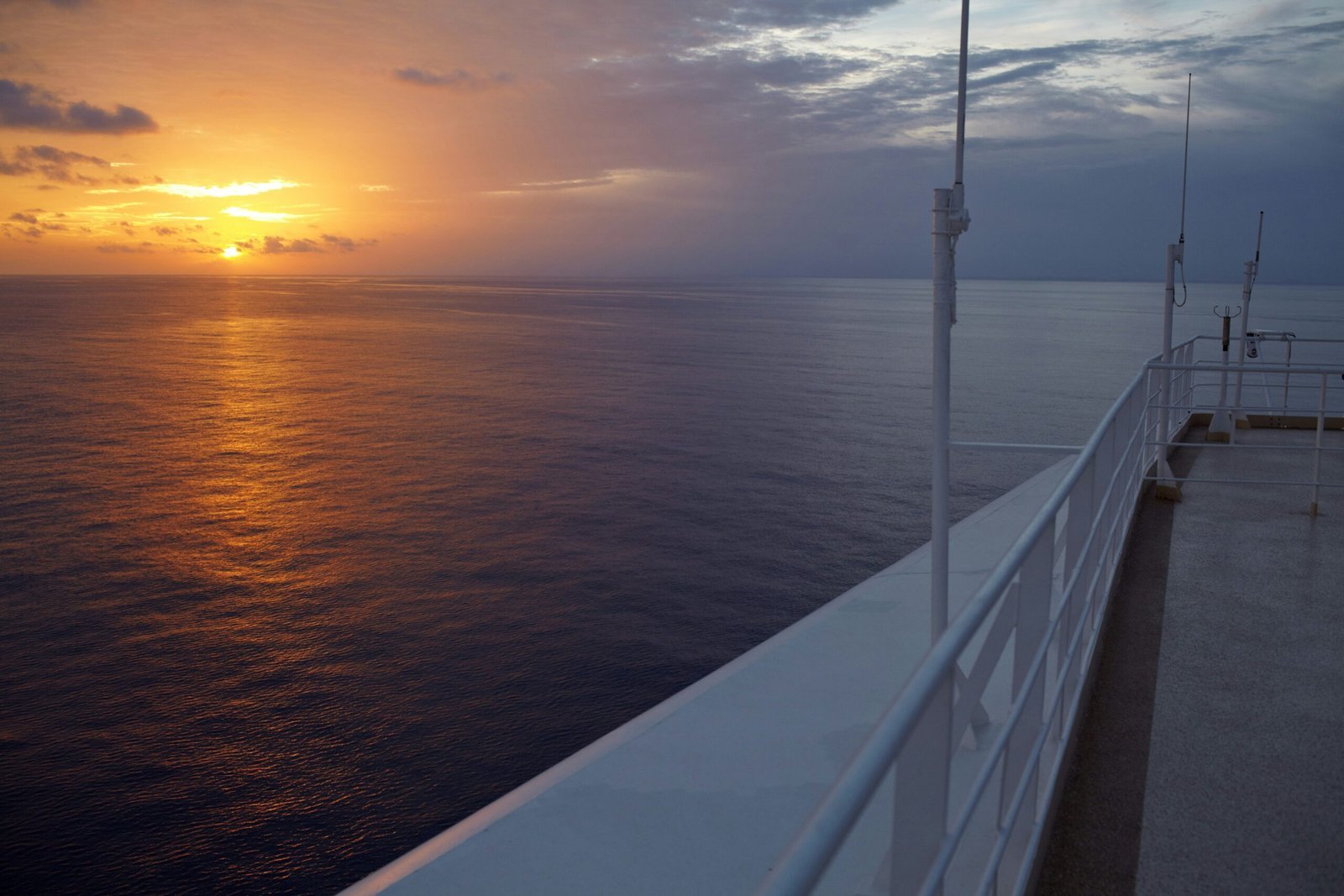 white metal railings near body of water during sunset